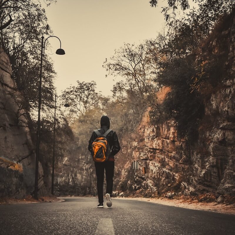 man in black jacket and black pants walking on road during daytime